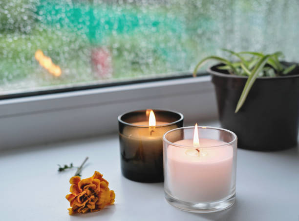 istock burning candles and orange autumn flower on a windowsill. rainy day and drops on a window. fall morning concept, hygge house. 1344688321