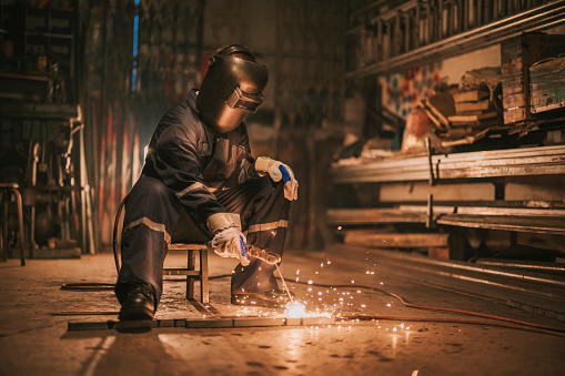 asian chinese female welder welding working in the workshop with welding torch repairing