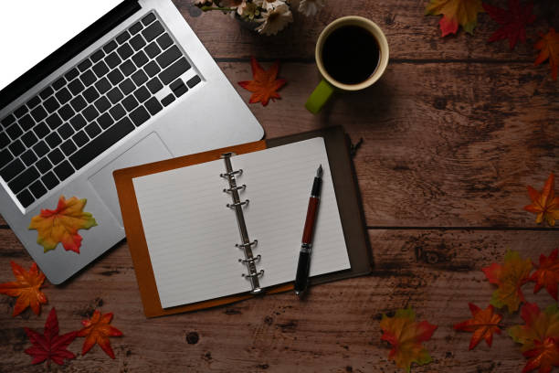 istock Notebook, Computer laptop, coffee cup and autumn maple leaves on wooden background. 1344693751