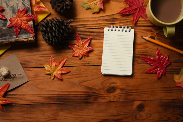 istock Empty notepad, coffee cup, pine cone and maple leaves on wooden table. 1344693791