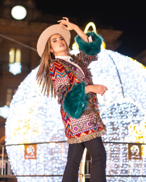 luci di natale in città, ragazza bionda caucasica in un cappello accanto a una gigantesca palla illuminata, stile di vita invernale - yoga winter urban scene outdoors foto e immagini stock