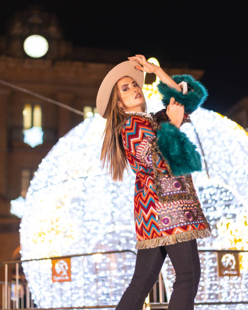 luci di natale in città, ragazza bionda caucasica appollaiata accanto a una palla gigante illuminata, stile di vita invernale - yoga winter urban scene outdoors foto e immagini stock