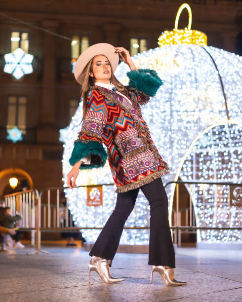 luci di natale in città, ragazza bionda caucasica in un cappello accanto a una palla gigante illuminata, stile di vita invernale, foto verticale - yoga winter urban scene outdoors foto e immagini stock