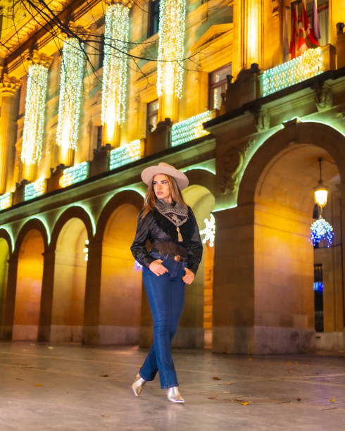 stile di vita invernale, ragazza bionda caucasica che indossa jeans e una giacca nera in città illuminata per natale di notte - yoga winter urban scene outdoors foto e immagini stock