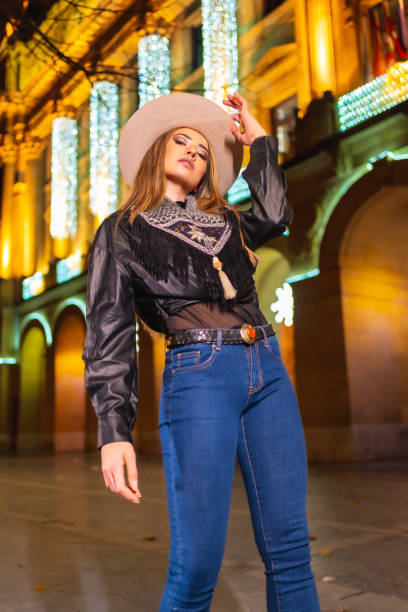 stile di vita invernale, giovane modella bionda caucasica che indossa jeans e una giacca nera in città illuminata per natale di notte - yoga winter urban scene outdoors foto e immagini stock