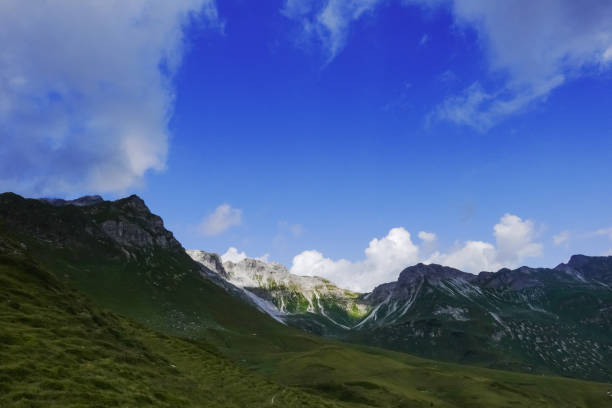 istock rocky mountains with green meadows and blue sky 1344701442