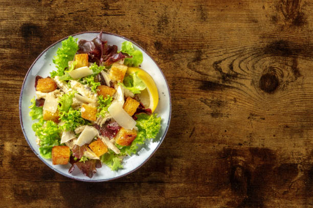 istock Chicken Caesar salad, shot from above on a dark rustic wooden background 1344703548