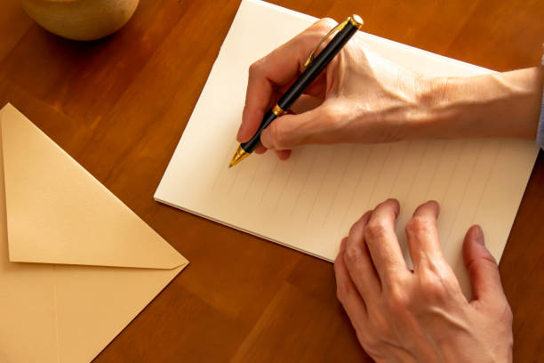 Hands holding stationery, envelopes, ballpoint pens, coffee and pens placed on the table