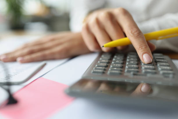istock Accountant hand pressing buttons on calculator at table with documents closeup 1344705457