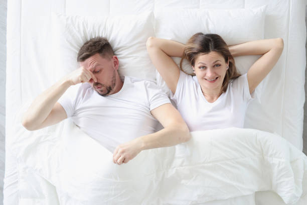 Married couple lying in bed. Man covering his nose with his hand Married couple lying in bed. Man covering his nose with his hand. Increased gassing concept tear gas photos stock pictures, royalty-free photos & images