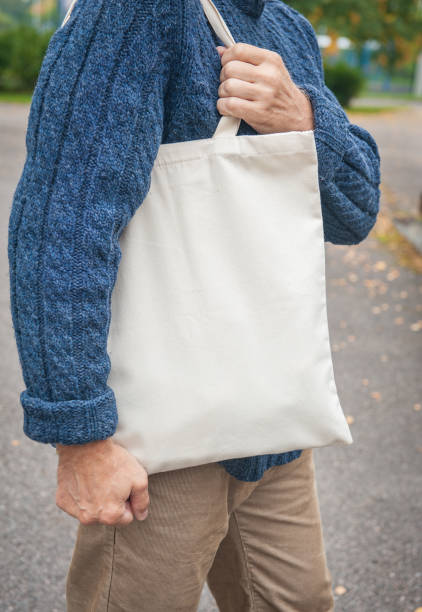 istock Stylish man holding white blank canvas tote shopping bag 1344707375