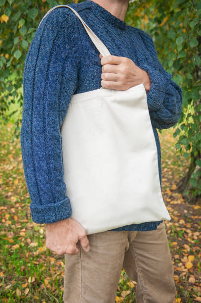 istock Stylish man holding white blank canvas tote shopping bag 1344707431