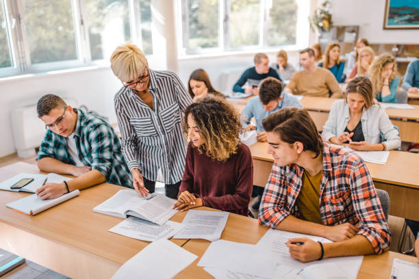 istock Happy senior professor assisting her students on a class in the classroom. 1344710809