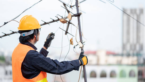 Asian worker repairing an old TV antenna on rooftop stock photo