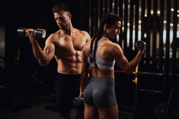 istock Young couple working out in the gym using dumbbells for bicep curls 1344715291