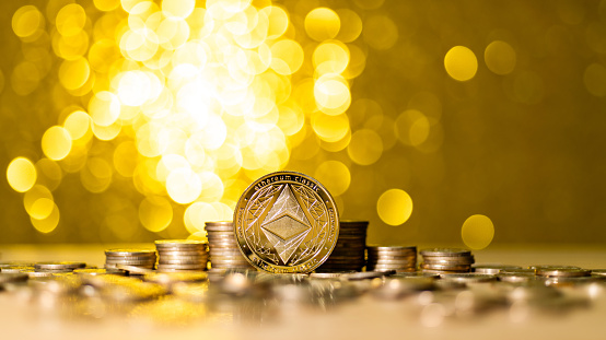 Fujian, China - August 26, 2021: Heap of Ethereum on shiny golden background.