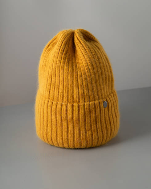 istock Small yellow knitted hat on grey background. woolly hat Closeup. 1344719564