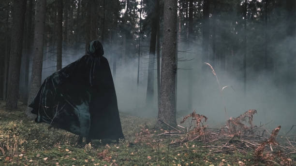 un misterioso hombre con un impermeable está caminando a través de un bosque brumoso. fondo místico. - bruja fotografías e imágenes de stock