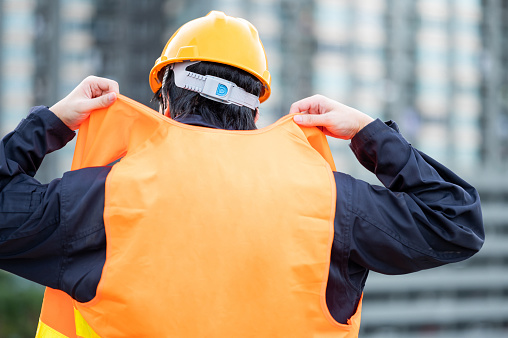 Asian maintenance worker man wearing reflective vest and safety helmet working at construction site. Civil engineering, Architecture builder and building service concepts