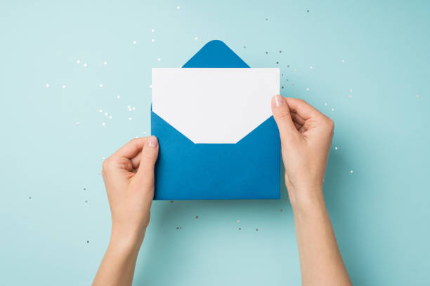 空きスペースを持つ孤立したパステルブルーの背景にスパンコールの上に白いカードで開いた青い封筒を保持している手の一人称トップビュー写真 - invitation birthday card creativity ideas ストックフォトと画像