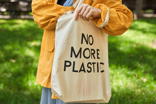 istock Woman taking something from her eco bag with slogan while standing at the park 1344726886