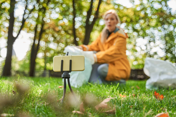 istock Volunteer woman crouching with bag while picking up trash at the park 1344726916