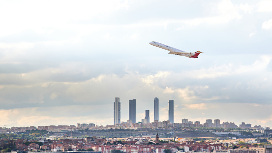 Madrid, Spain; 09-25-2021: Mitsubishi Crj -1000 aircraft of the Iberia Regional airline taking off from Madrid airport leaving behind a panorama of its famous office towers