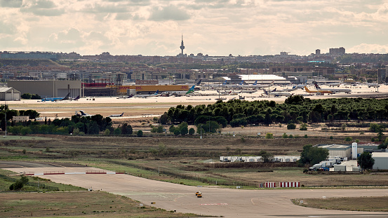 Madrid, Spain; 09-25-2021: Runway at Madrid Barajas airport with airport services cars circulating on it with views of the city and its tv tower called \