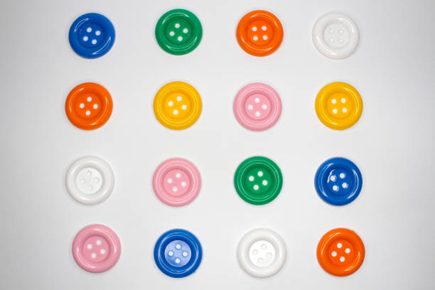 Directly above shoot of colorful sewing buttons arrangement patterns on white background.