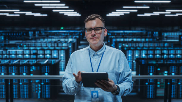 Portrait of a Data Center Engineer Using Laptop Computer. Server Room Specialist Facility with Adult Male System Administrator Working with Data Protection Network for Cyber Security. retrato de un ingeniero de centro de datos usando una computadora portátil. instalación especializada en sala de servidores con administrador de sistemas masculino adulto que trabaja con la red de protección de datos para la seguridad cibernética.