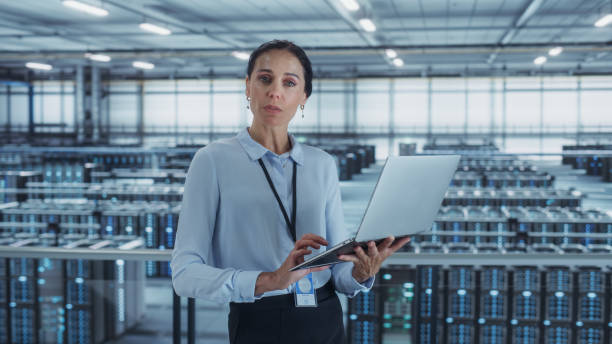 istock Portrait of a Female Data Center Engineer Using Laptop Computer. Server Room Specialist Facility with Multiethnic System Administrator Working with Data Protection Network for Cyber Security. 1344732061