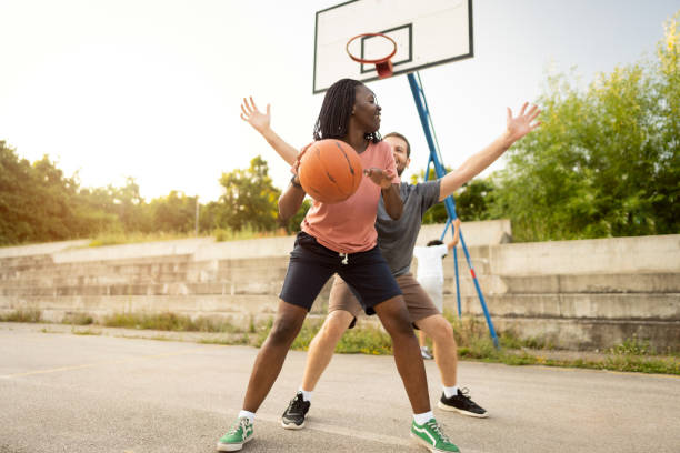 istock Active multiracial couple, having fun while playing outdoor pick-up basketball 1344733296