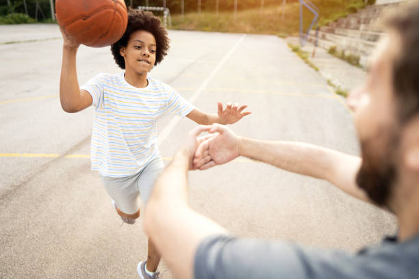 istock Father learning his daughter how to dunk during their outdoor basketball game, while he making imagined hoop with his hands 1344733519