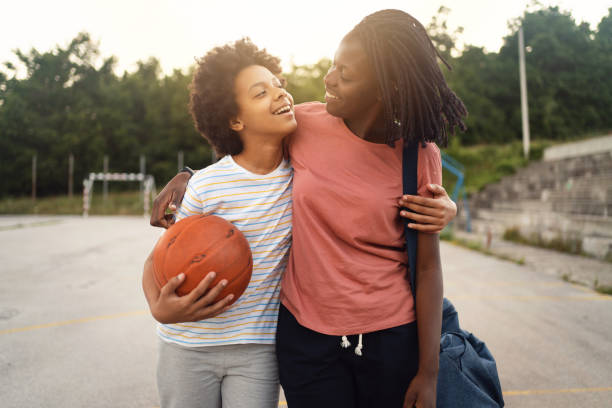 orgogliosa madre di etnia nera, che prende la figlia adolescente dal suo esercizio di basket - teen activity foto e immagini stock