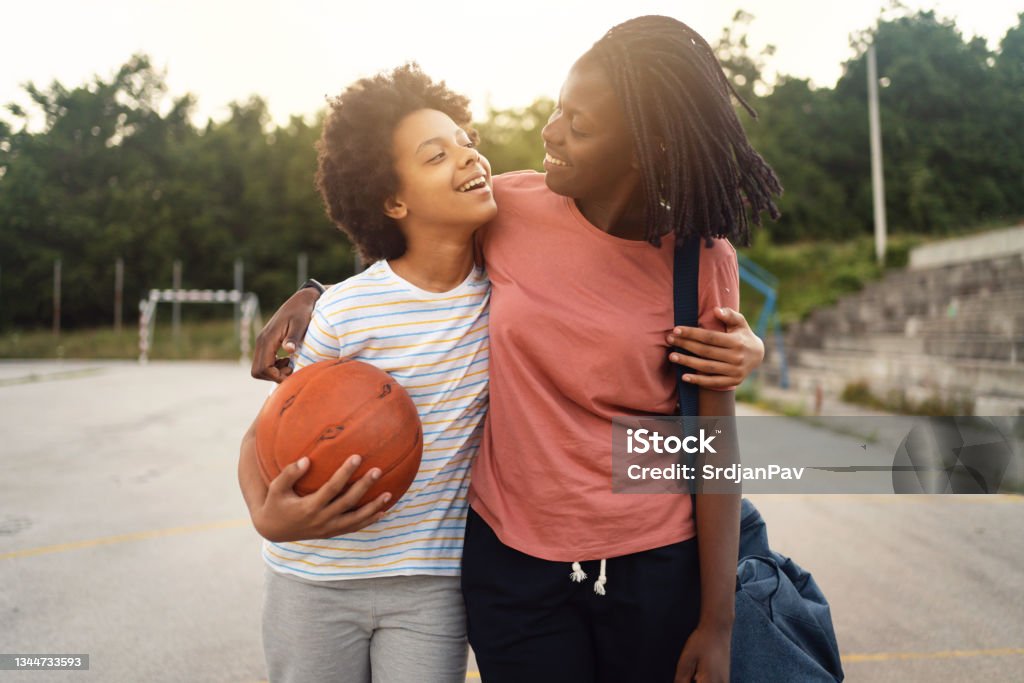 Proud mother of Black ethnicity, picking up her teenage daughter from her basketball practise Cheerful and proud mother of Black ethnicity, picking up her teen daughter from her basketball practise Teenager Stock Photo