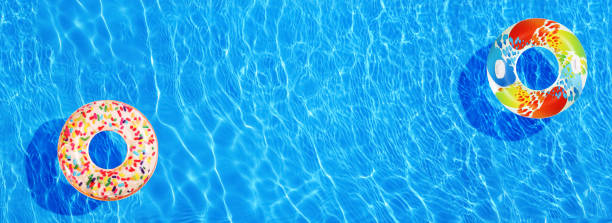 istock Different inflatable rings floating in swimming pool, top view. Banner design 1344733630