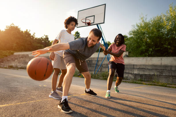 familia multirracial divirtiéndose mucho juntos mientras juegan baloncesto al aire libre - bouncing ball family playing fotografías e imágenes de stock