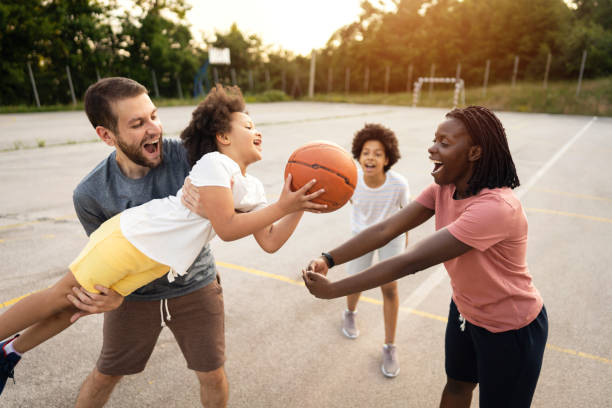 istock Multiracial stepfamily, an proud father, supporting and cheering his daughter while she trying to dunk into imagined hoop her mother made with her hands 1344733814