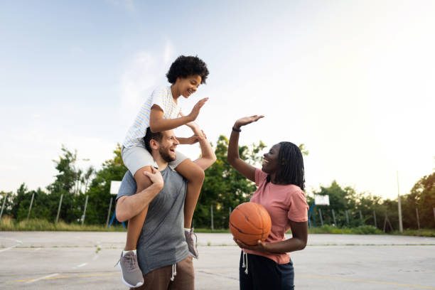 fröhlicher multirassischer stieffamilienaustausch high-five nach ihrem basketballspiel - parent playful father mother stock-fotos und bilder