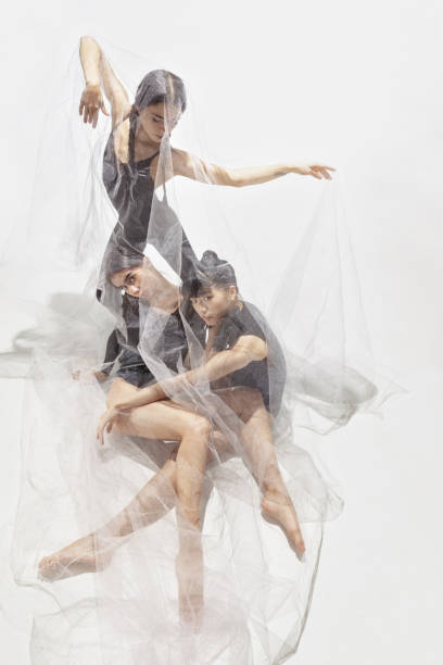 istock Modern ballet performance. Group of modern dancers at art contemp dance, Tree ballerinas under transparent voile fabric 1344735299