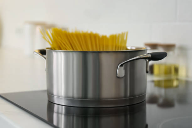 istock Saucepan with uncooked pasta on stove in kitchen, closeup 1344737445