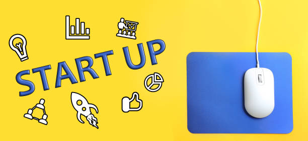 istock Modern wired optical mouse, different icons and word STARTUP on yellow background, top view. Banner design 1344737534