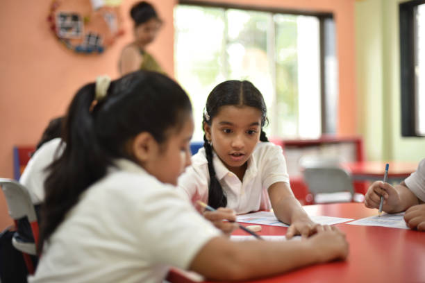 istock Girl student helping her classmate in worksheets 1344737663