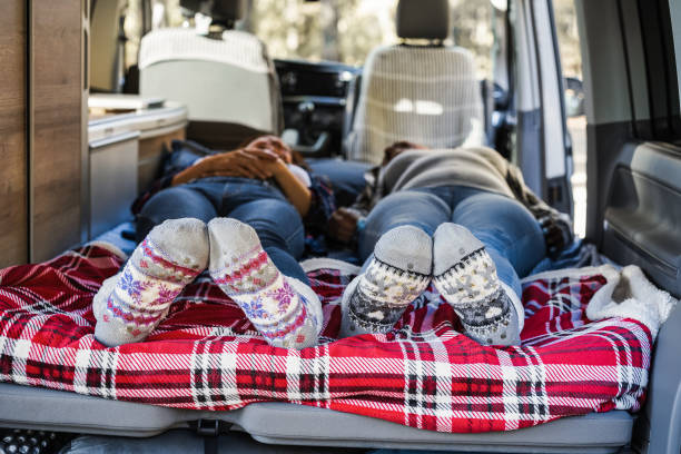 Mature women sleeping inside mini van camper wearing Christmas warm socks - Focus on feet stock photo