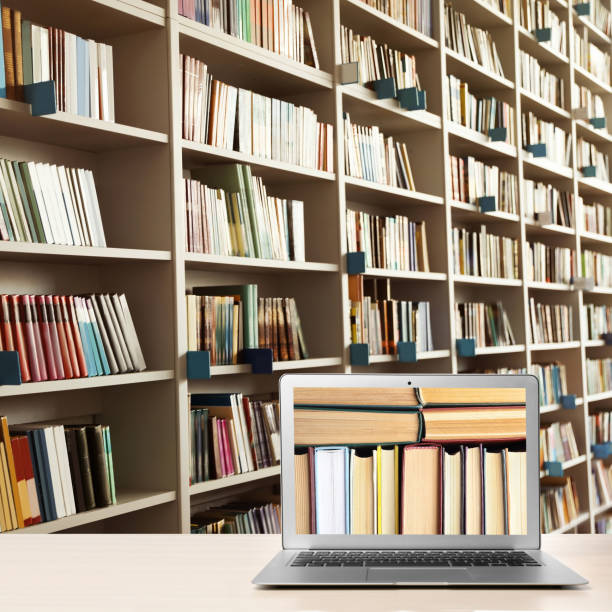 istock Digital library concept. Modern laptop on table and shelves with books indoors 1344740473