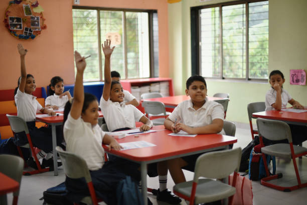 istock School children sitting in classroom raising hands 1344740690