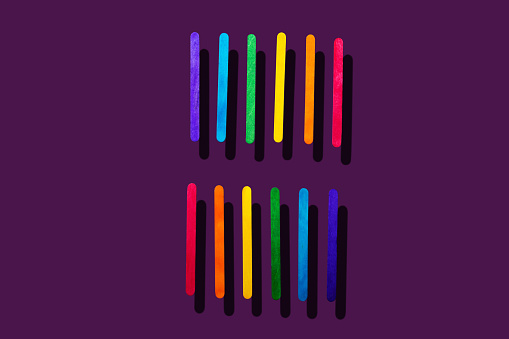 Rows of paralell wooden craft sticks in opposite order cut out on purple background