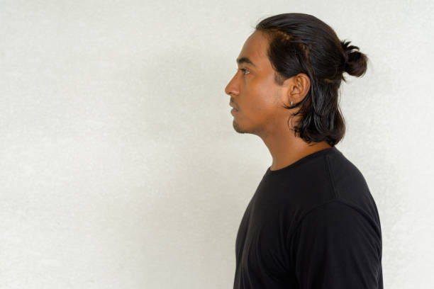 Profile view shot of handsome young Indian man against plain background outdoors shot with natural light
