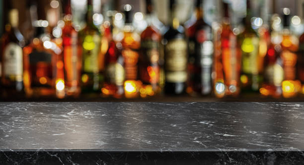 grey table top and beautiful bokeh shelves with alcohol bottles at the background. bar concept. - table top shot fotos stockfoto's en -beelden