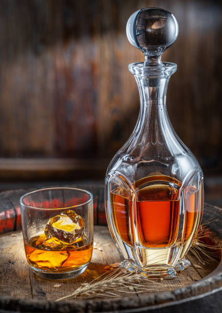 jarra de whisky y vaso de whisky sobre viejo barril de madera en el fondo oscuro. - gin decanter whisky bottle fotografías e imágenes de stock